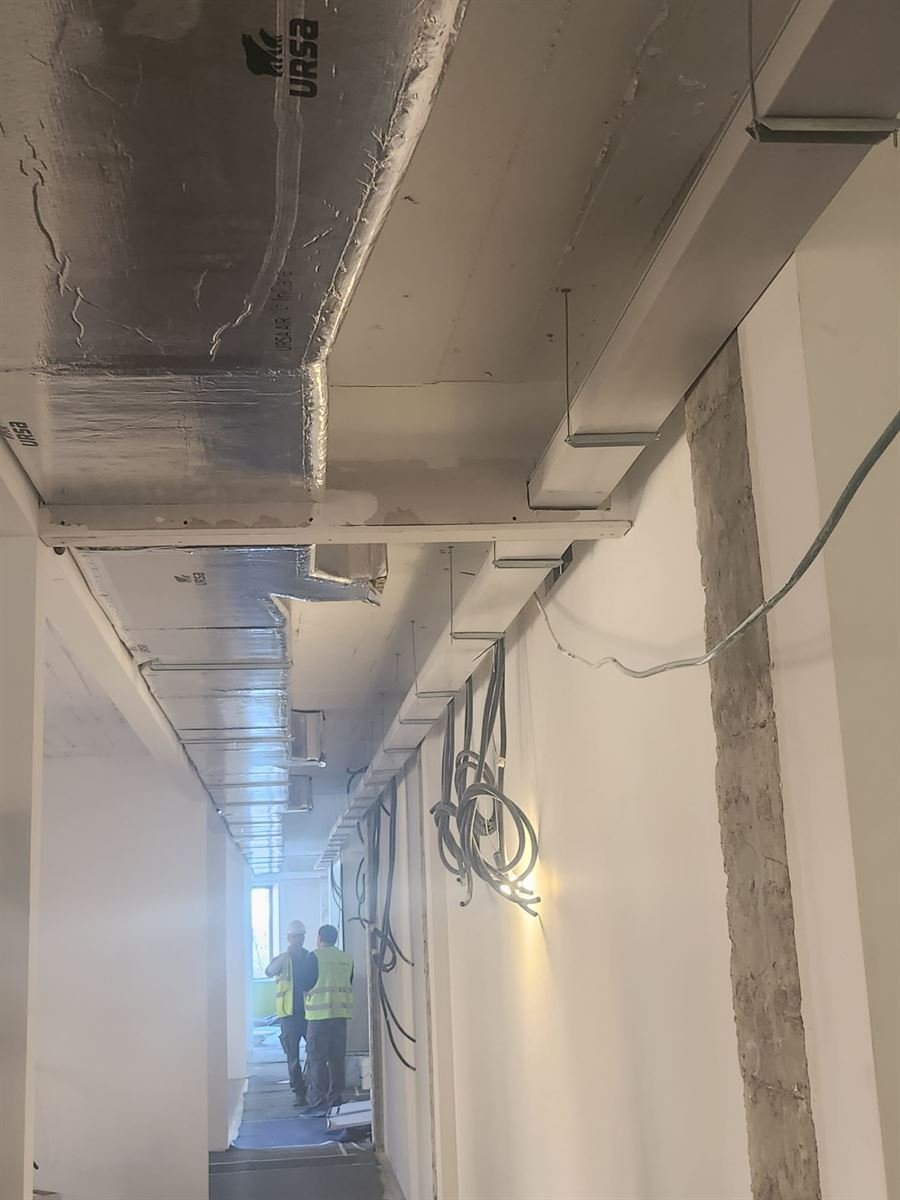Conductos de fibra instalados en el techo de un pasillo durante la obra, con el cableado todavía a la vista