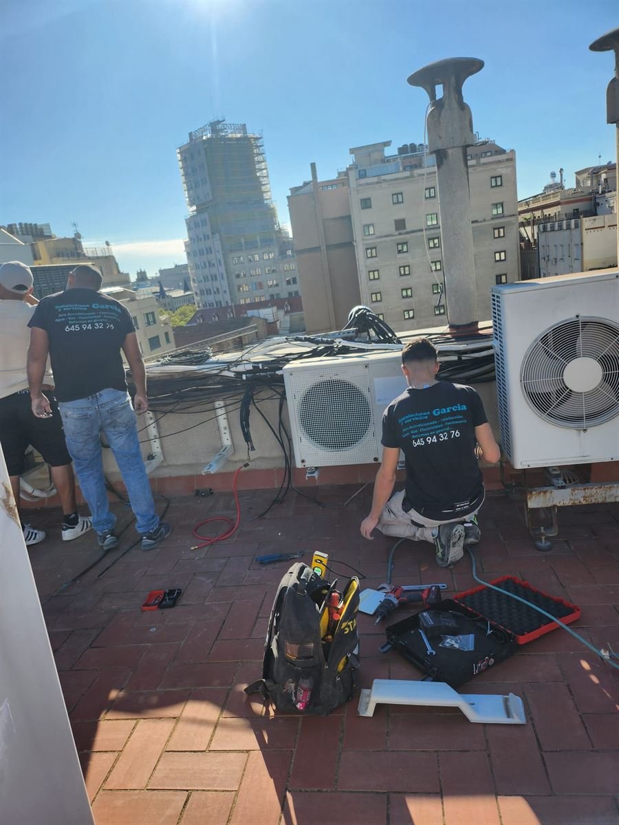 Técnicos de Instalaciones y Servicios JGDR instalando las unidades exteriores en la cubierta del edificio