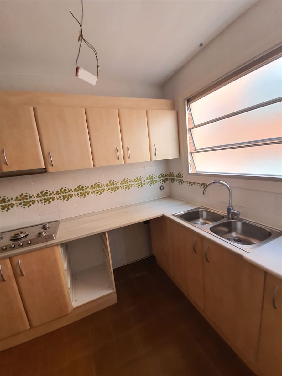 La cocina antes de la reforma, con el mobiliario de madera y el alicatado con cenefa