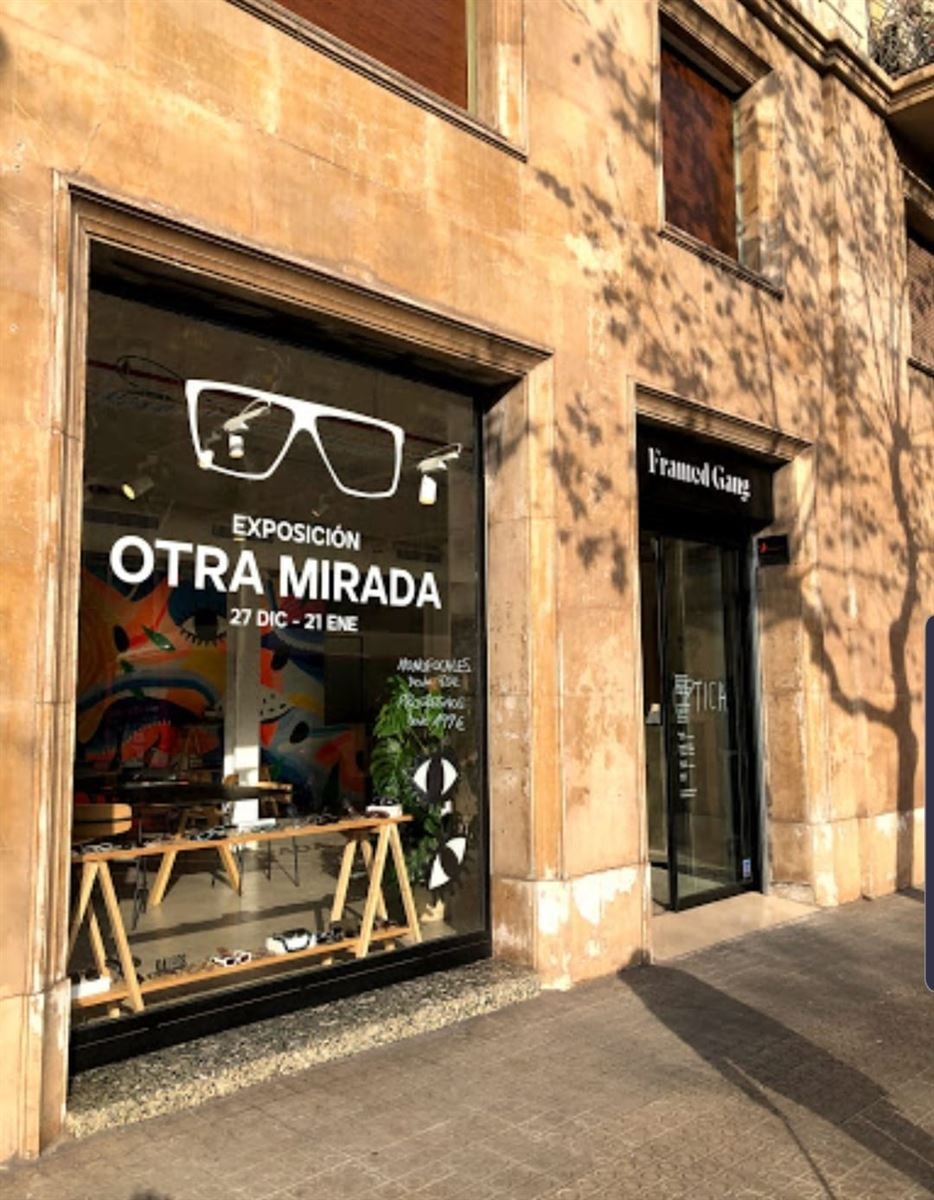 Fachada de la óptica en un edificio de piedra, con el escaparate rotulado