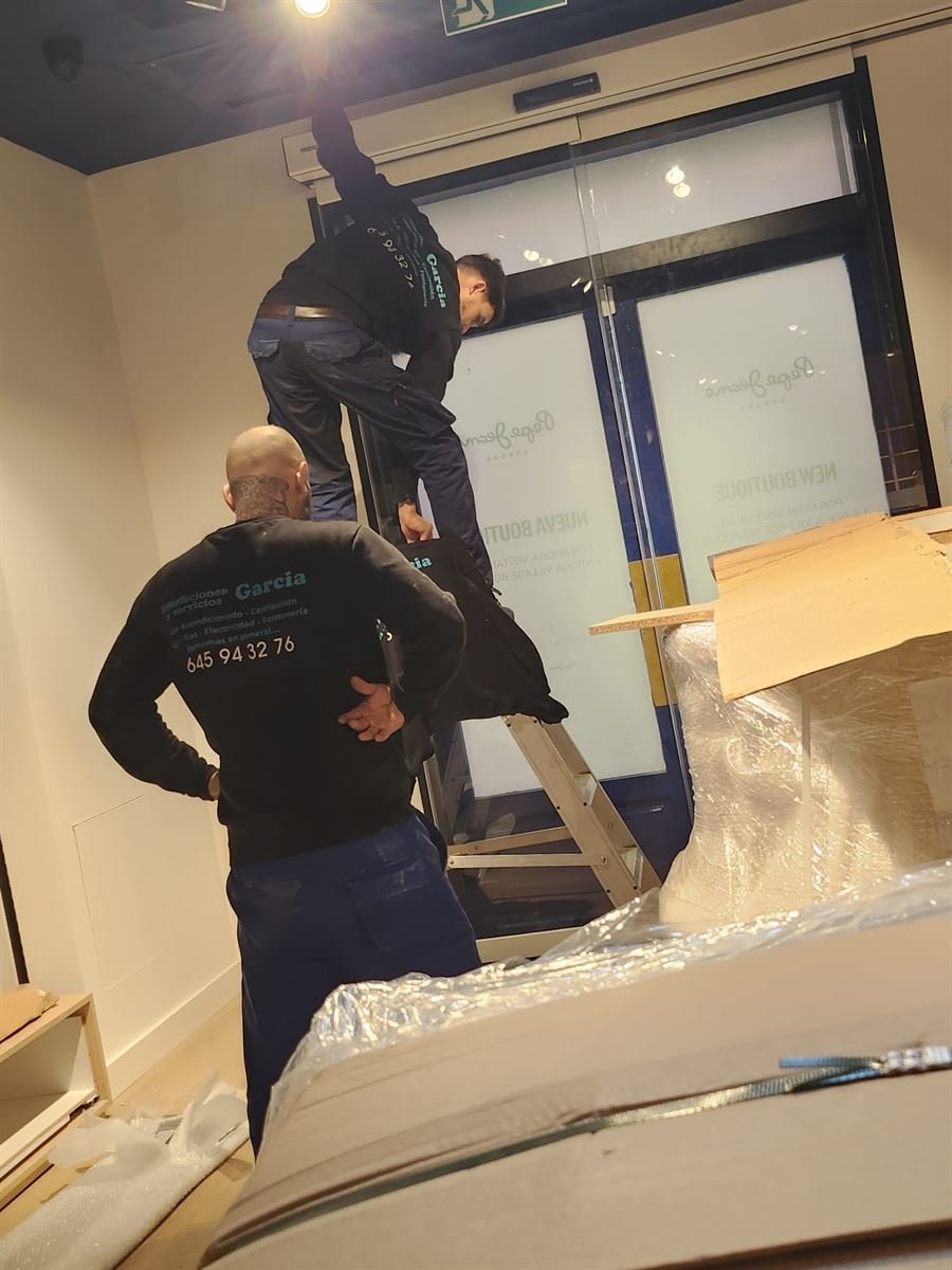 Dos técnicos de Instalaciones y Servicios JGDR trabajando en la entrada de la tienda