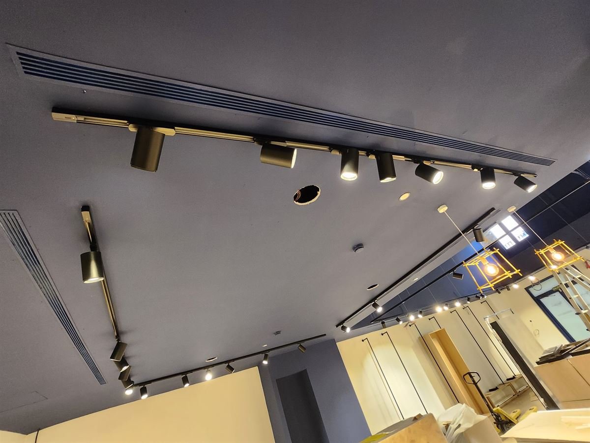 Falso techo de la sala de ventas con los difusores lineales y los carriles de iluminación instalados