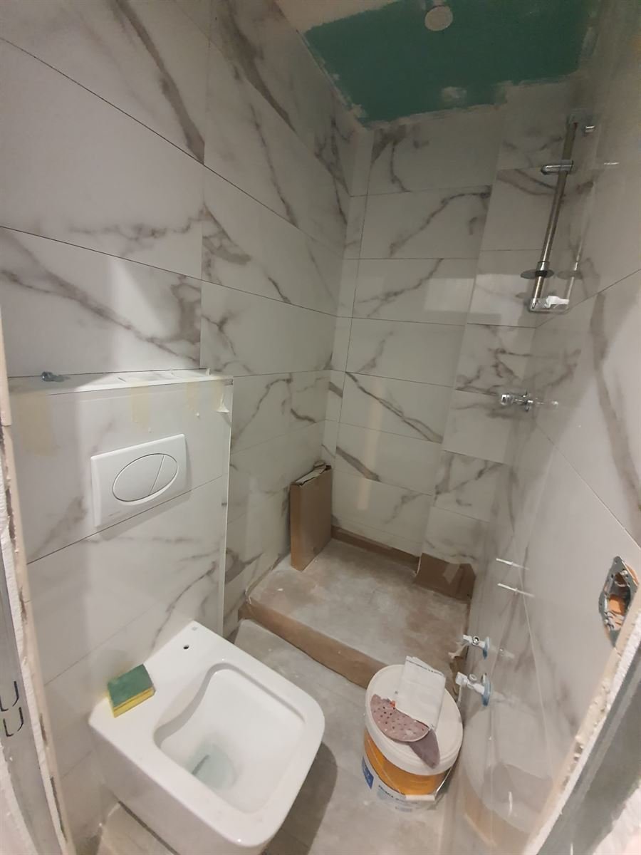 El baño con el alicatado puesto y el inodoro suspendido montado, antes de los remates