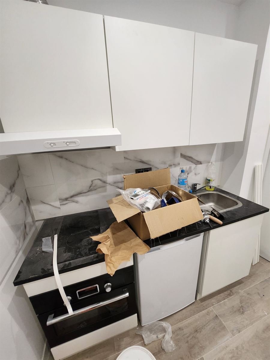 Cocina acabada con la encimera negra, la campana, el horno y el fregadero instalados