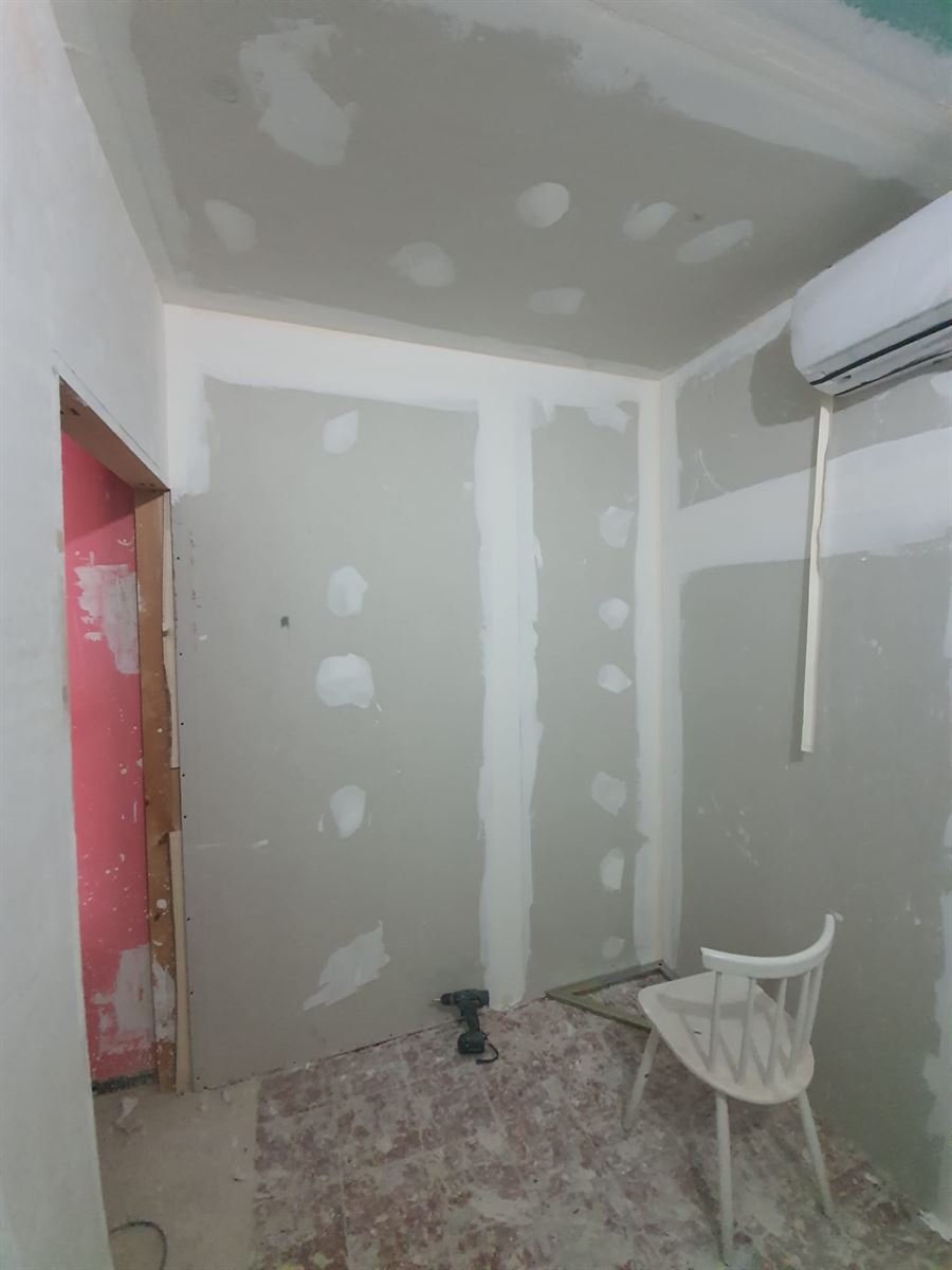 Estancia con los trasdosados de pladur tratados y la unidad interior de aire acondicionado ya colgada