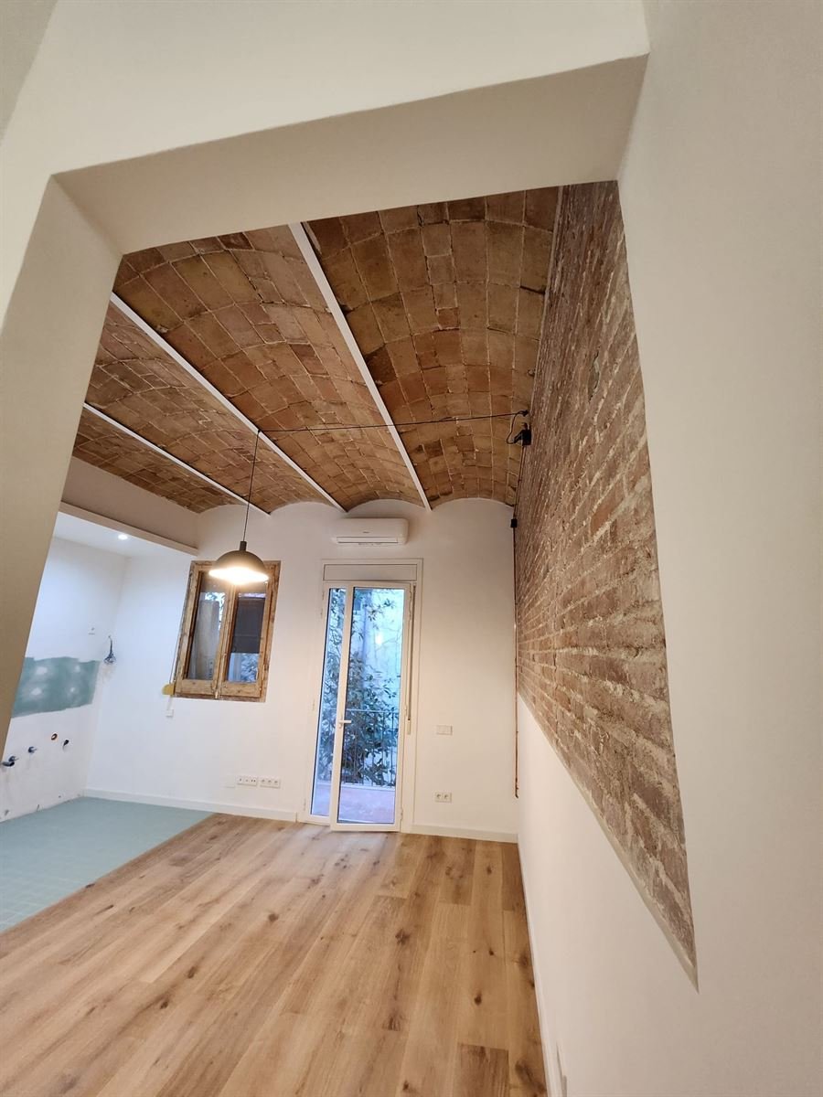 Estancia terminada con la bóveda catalana a la vista, la pared de ladrillo visto y el pavimento nuevo