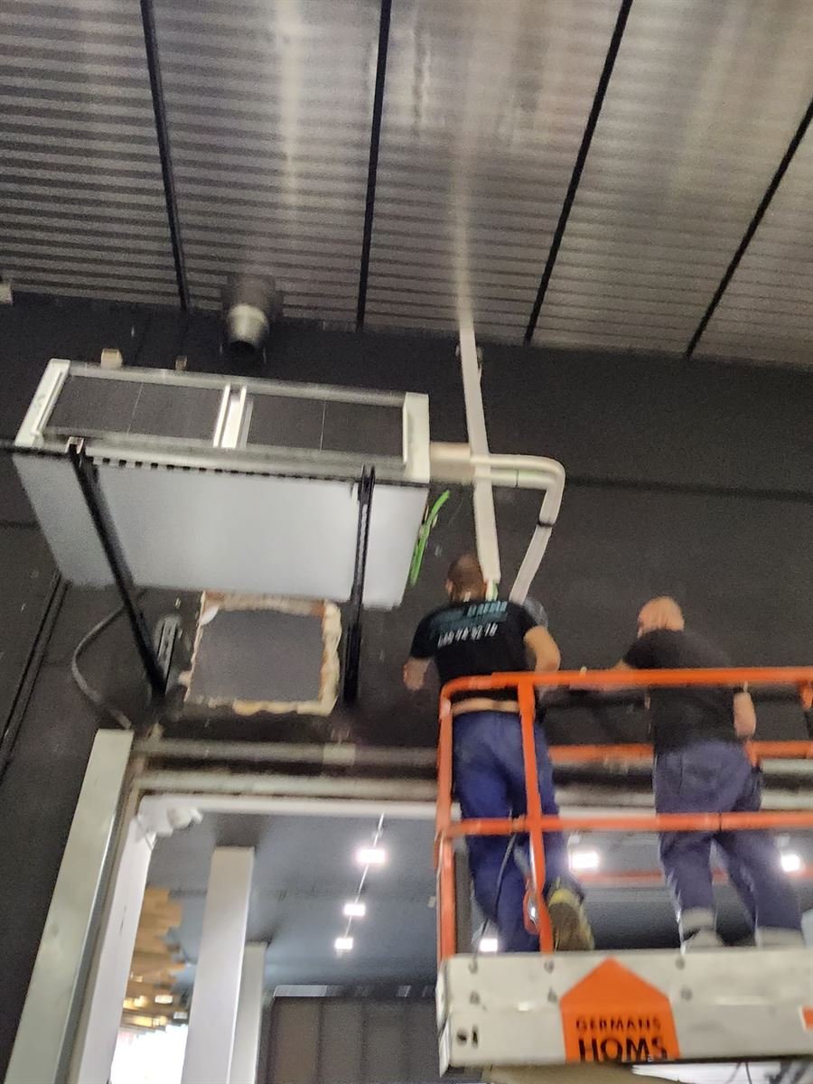 Dos técnicos de Instalaciones y Servicios JGDR colgando una unidad interior desde una plataforma elevadora